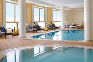 利雅德利雅得会议中心万豪行政公寓式酒店的酒店大堂的游泳池,配有桌椅