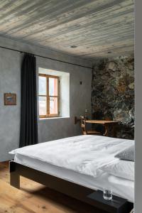 阿尔代兹Ein Kraftort und architektonisches Juwel的卧室配有一张白色大床和石墙