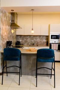 内罗毕Exquisite 2BD at Skynest Residences with rooftop heated pool的厨房在柜台前设有2把蓝色椅子
