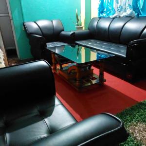 佩林OYO Home Narayan Homestay & Adventures的客厅配有黑色真皮座椅和玻璃桌