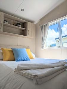 纽基Large 4 person Couples and Family Caravan in Newquay Bay Resort的一张带黄色和蓝色枕头的床和窗户