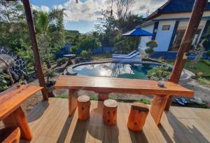 金塔马尼Batur Happy House的甲板上的木桌和凳子,甲板上设有游泳池