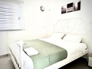 纳哈里亚Vacation Apartment by The Sea - Achziv的白色卧室内的白色床和白色婴儿床