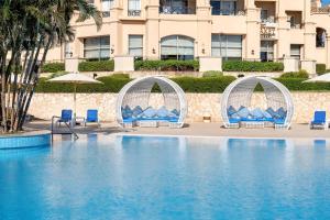 沙姆沙伊赫沙姆沙伊赫克娄巴特拉豪华度假酒店的一个带椅子和遮阳伞的游泳池和一座建筑