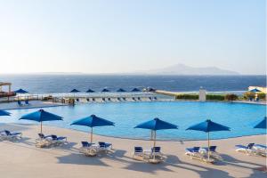 沙姆沙伊赫沙姆沙伊赫克娄巴特拉豪华度假酒店的一个带蓝色遮阳伞和椅子的大型游泳池,并享有海景。