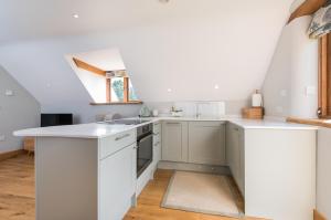 白金汉Exquisite Coach House Near Silverstone & Stowe的厨房配有白色橱柜和窗户。