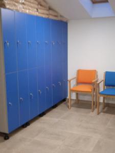 MaellaAlbergue de Maella的一间有两把椅子的房间里一排蓝色的储物柜
