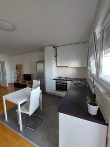 萨格勒布Apartment City的厨房配有白色橱柜和白色的桌椅