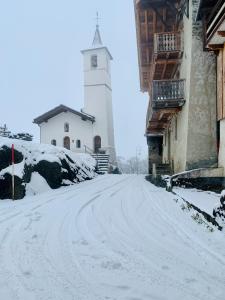 VillarogerChalet Violettes的一条有雪覆盖的街道,后面有一座灯塔