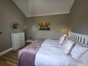 利斯坎诺Rose Meadow Lodge的卧室配有白色大床和梳妆台