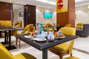 阿尔及尔Hotel Hammamet的一间食堂,配有桌椅和食物