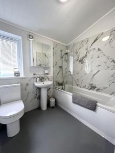 克利夫罗Diddly Squat Lodge with hot tub, Pendle View Holiday Park的白色的浴室设有卫生间和水槽。