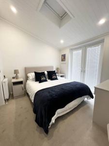 克利夫罗Diddly Squat Lodge with hot tub, Pendle View Holiday Park的白色卧室设有一张大床和两个窗户