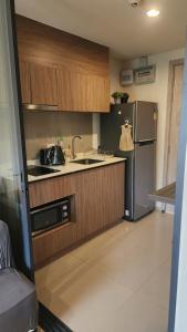 华欣Apple's La casita condo in Hua Hin的厨房配有木制橱柜和不锈钢冰箱。