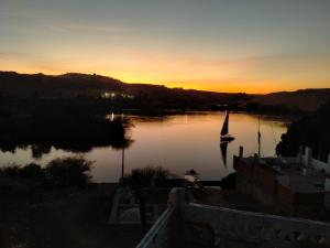 阿斯旺Seko Kato Nile View Hostel的河上日落,船上有船