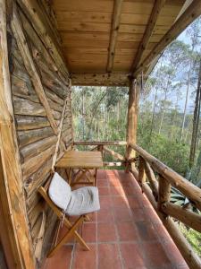 昆卡The Hideout- A Cabin in Nature; 25 min from Cuenca的小木屋的门廊,配有长凳和椅子