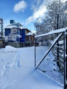 乌斯怀亚hostel comunidad Ushuaia的房屋前有雪覆盖的栅栏