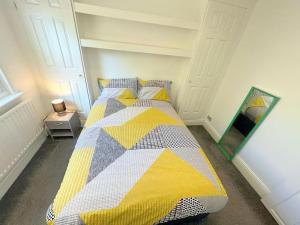 萨顿Spacious 1-bedroom Flat in Sutton (South London)的一间卧室配有一张带黄灰色被子的床