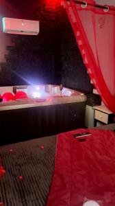 维特罗勒Douceur d’une nuit (studio avec jaccuzi privatif)的一间设有床铺和浴缸及红色窗帘的房间