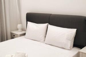 沃洛斯Φιλόξενο σπίτι στο Βόλο的一张带白色枕头和黑色床头板的床
