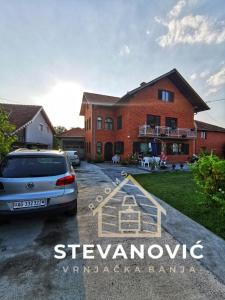 VrnjciStevanovic Smestaj的前面有停车位的房子