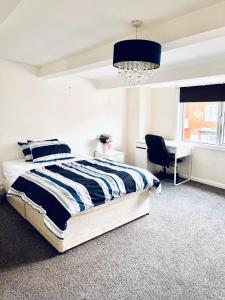 利兹Private Room close to Leeds University and City centre的一间卧室配有一张床、一张书桌和一个吊灯。