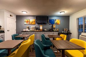 图莱里Quality Inn & Suites的餐厅设有木桌和黄色椅子