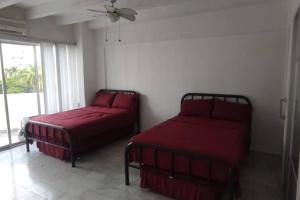 阿卡普尔科Fresca estancia en zona Dorada con Alberca/Playa!的一间卧室设有两张带红色床单的床和窗户。