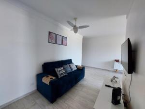 佩鲁伊比Apartamento Peruíbe的客厅配有蓝色的沙发和平面电视。