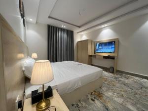 AR Rummanahسويت إم للأجنحة الفندقية的配有一张床和一台平面电视的酒店客房
