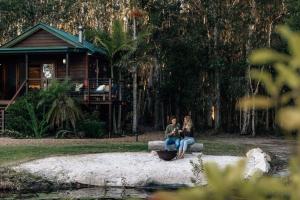 佩里吉安比奇努萨维巴湖屋舍酒店的两个人坐在房子前面的长凳上