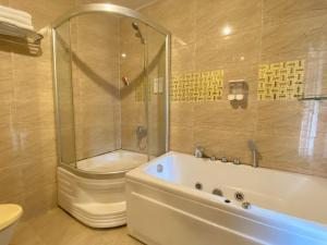 胡志明市CROWNE BUI VIEN Hotel的带浴缸、淋浴和卫生间的浴室