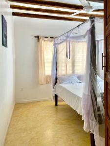 拉穆Beautiful Mafriza Apartment的一间卧室配有一张带天蓬和窗户的床