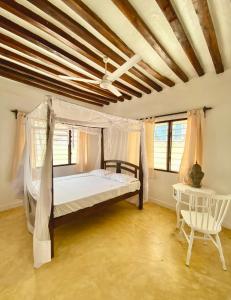 拉穆Beautiful Mafriza Apartment的一间卧室配有一张天蓬床和一把椅子