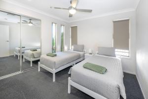 布里斯班Large house 7 mins from Airport的白色的客房配有两张床和镜子