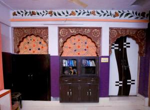 焦特布尔Banasa Heritage Haveli的一间拥有紫色墙壁、电视和两个十字架的房间