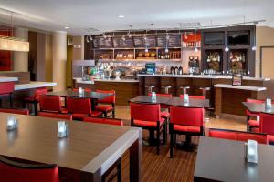 帕拉默斯Courtyard by Marriott Paramus的一间带桌子和红色椅子的餐厅和一间酒吧