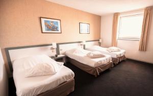 卢尔德天堂酒店的酒店客房设有两张床和窗户。