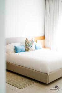 佩雷贝勒Black Marlin Apartments的一张带白色床单和蓝色枕头的床