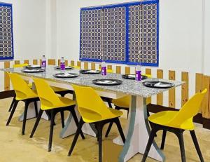 Jyoti GaonManas Jungle Retreat的客房内的一张带黄色椅子的餐桌
