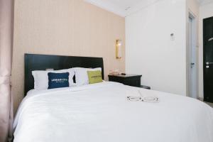 DauUrbanview Hotel Sultan Palace Malang by RedDoorz的卧室配有白色的床和2杯眼镜