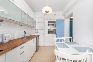 华沙Czapelska 40 by Homeprime的厨房配有白色橱柜和桌椅