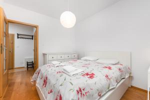华沙Czapelska 40 by Homeprime的白色卧室配有一张带花卉床罩的床