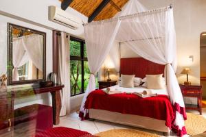 赫卢赫卢韦Leopard Walk Lodge的一间卧室设有一张天蓬床和大窗户
