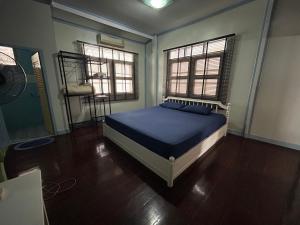 华欣ThaiTae GuestHouse HuaHin的一间卧室配有一张带蓝色床单的床和两个窗户。