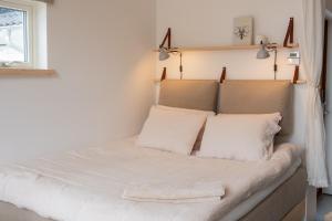 KullavikMalevik Tiny House的一间卧室配有带白色床单和枕头的床。