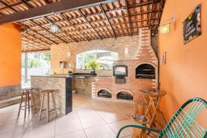 马里卡Espaço Ideal de Itaipuaçú的一间设有砖砌壁炉的厨房和一间带凳子的酒吧