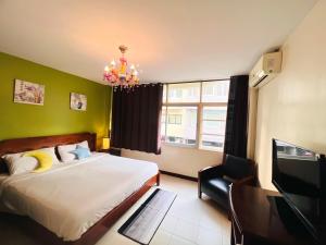 华欣Baan Nilawan Hua Hin Hotel的一间卧室配有一张床、一台电视和吊灯。