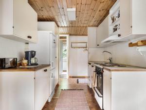 穆塔拉Chalet Västanvik Snickarhagen - OST047 by Interhome的厨房配有白色橱柜和木制天花板