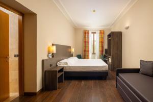 佛罗伦萨贝坦尼亚别墅酒店的一间卧室配有一张床和一张沙发